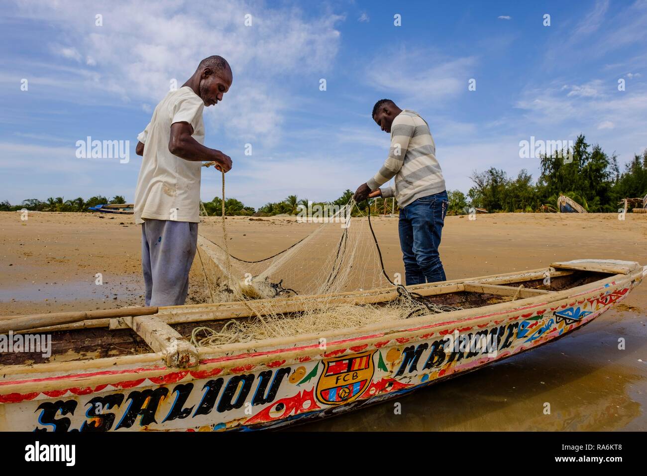 I pescatori mettere le loro reti nella loro tradizionale barca da pesca, Saly, regione di Thiès, Senegal Foto Stock
