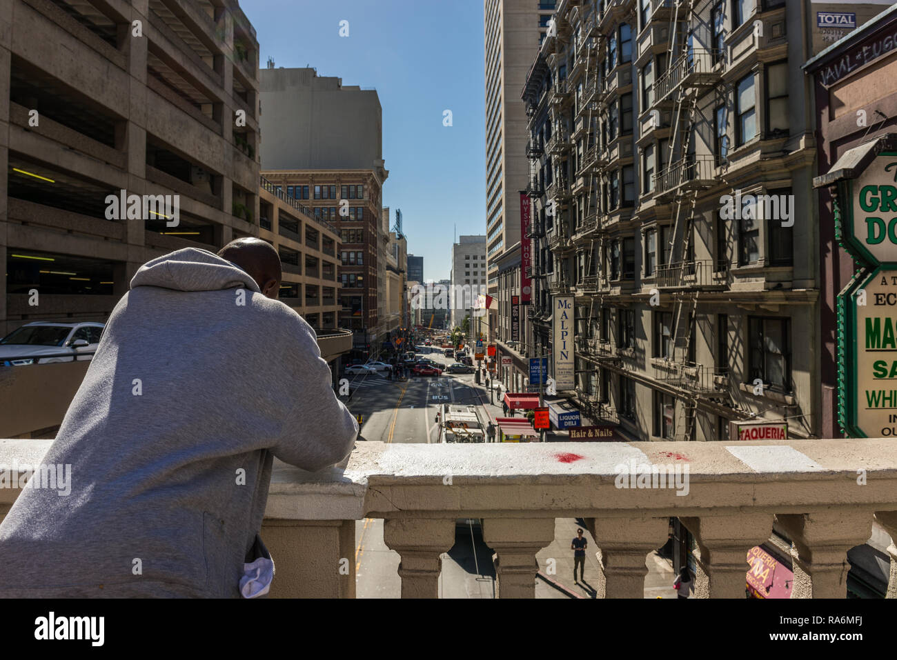 Un afro-americano con una felpa bianca si appoggia su un mancorrente a Bush Street di San Francisco, California, Stati Uniti d'America Foto Stock