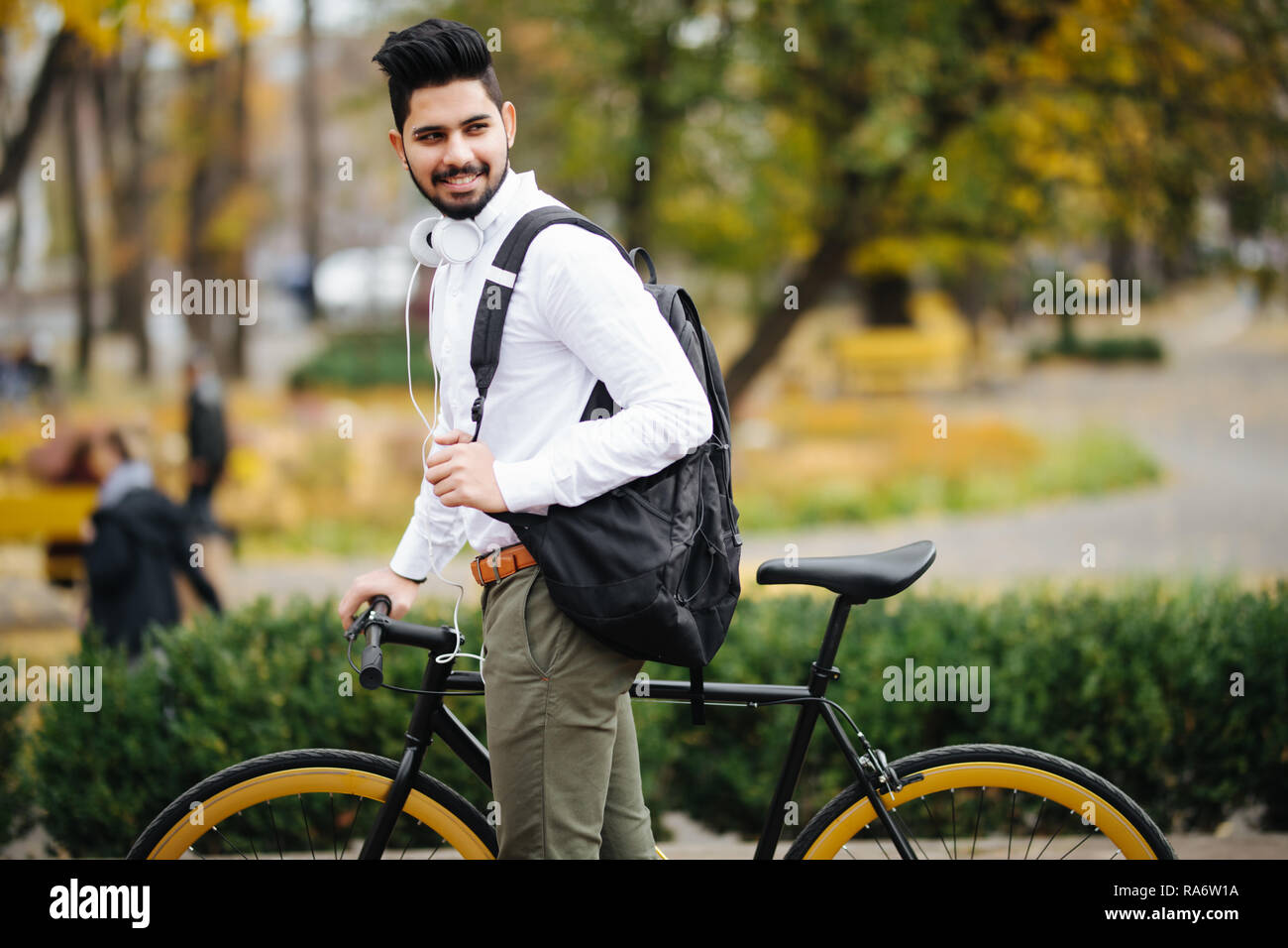 Casual commerciante indiano spingendo la bicicletta e trasportare handsbag di andare al lavoro in bicicletta Foto Stock