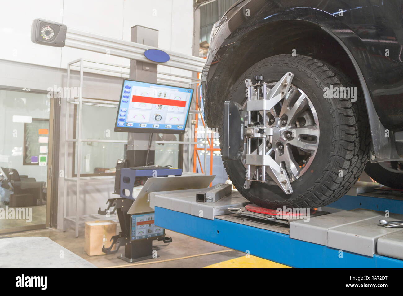 Una vettura sul volante della macchina equilibratrice e calibrare con riflettore laser fissare su ciascun pneumatico al centro la guida regolare in garage Foto Stock