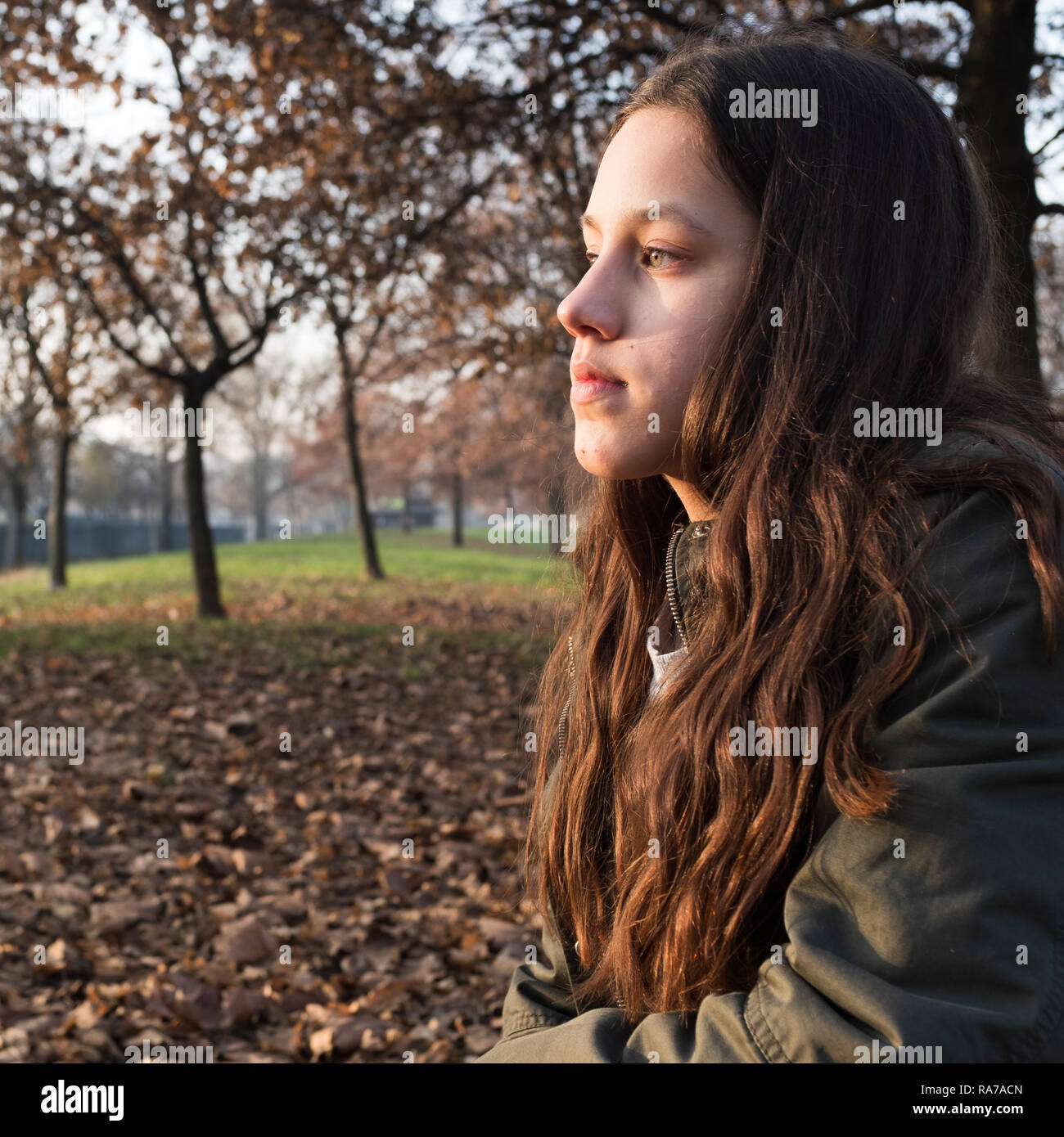 Pensieroso. Attraente giovane adolescente che guarda lontano nella contemplazione, un autunno sfondo con fogliame e alberi. Foto Stock