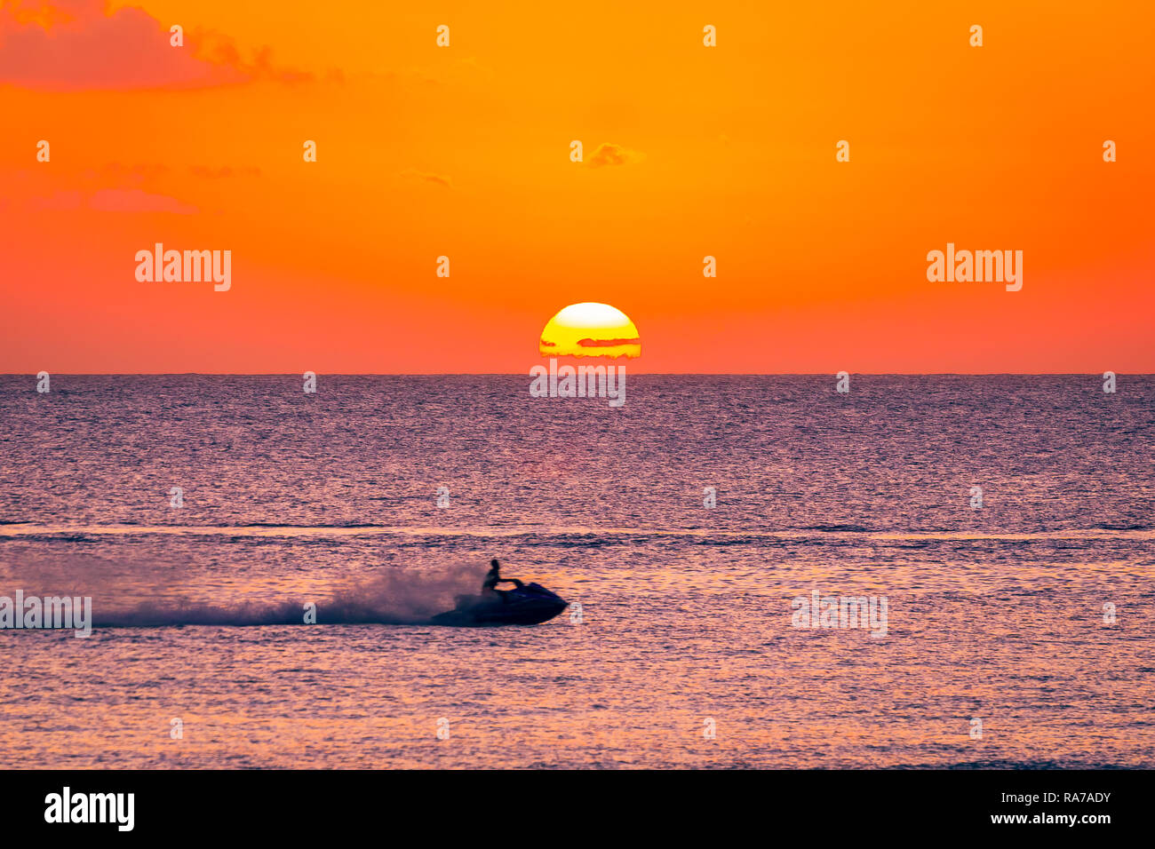 Tobago, Caraibi, West Indies, giovane pilota su un jet ski al tramonto godendo della libertà e la fuga sul vasto oceano con glorioso ambiente SUN. Foto Stock