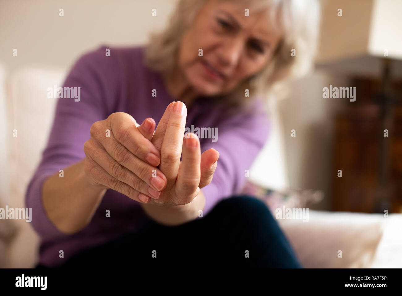 Senior donna a casa la sofferenza con artrite Foto Stock