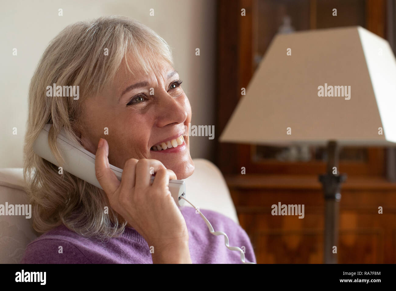 Sorridente donna Senior usando il telefono di casa Foto Stock