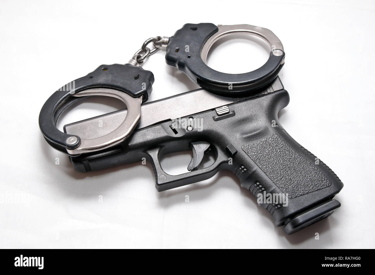 Una coppia di colori nero e argento manette recante sulla parte superiore di un nero semi pistola automatica su sfondo bianco Foto Stock
