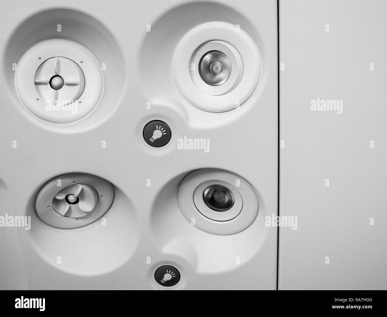 Close-up nella console a padiglione pannello con icona della lampadina, luce pulsante e impianto di aria condizionata in cabina di basso costo classe economy in airplan commerciale Foto Stock