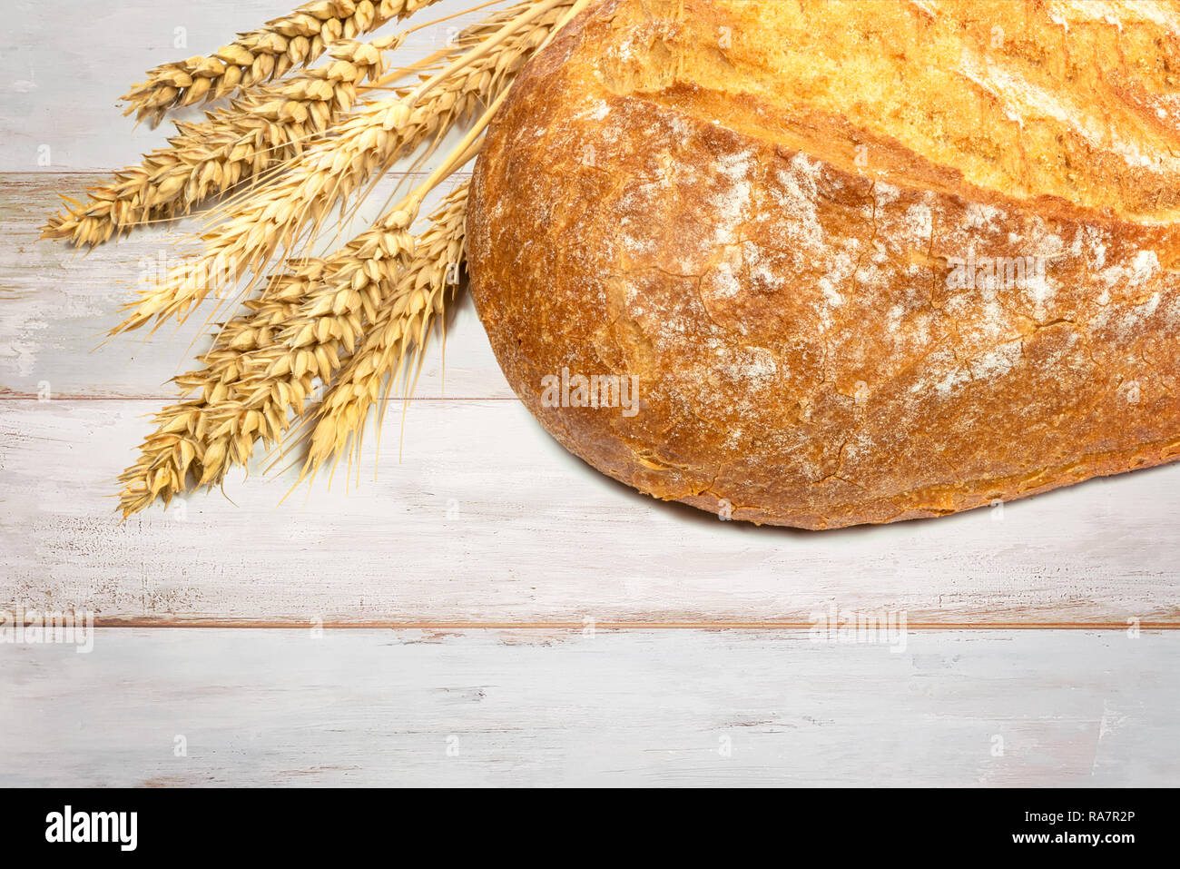 Nuovo filone di pane con chicchi di grano su una tavola di legno tabella vintage in stretta verso l'alto. Foto Stock