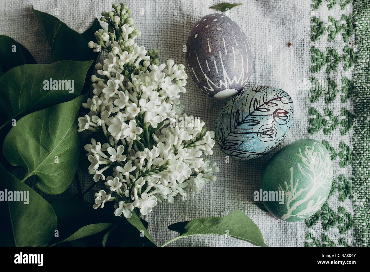 Le uova di pasqua con motivi floreali e ornamenti di pulcino su sfondo rustico con fiori lilla. vista dall'alto. spazio per il testo. felice Pasqua. greeting card concept. st Foto Stock