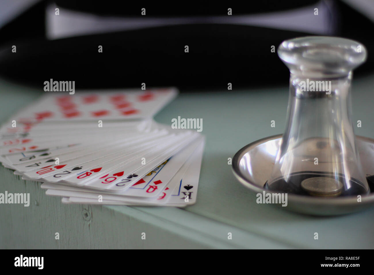 Attrezzatura di un mago. Schede, vetro, monete, tubo da stufa hat su un dipinto di cassa di legno. Foto Stock