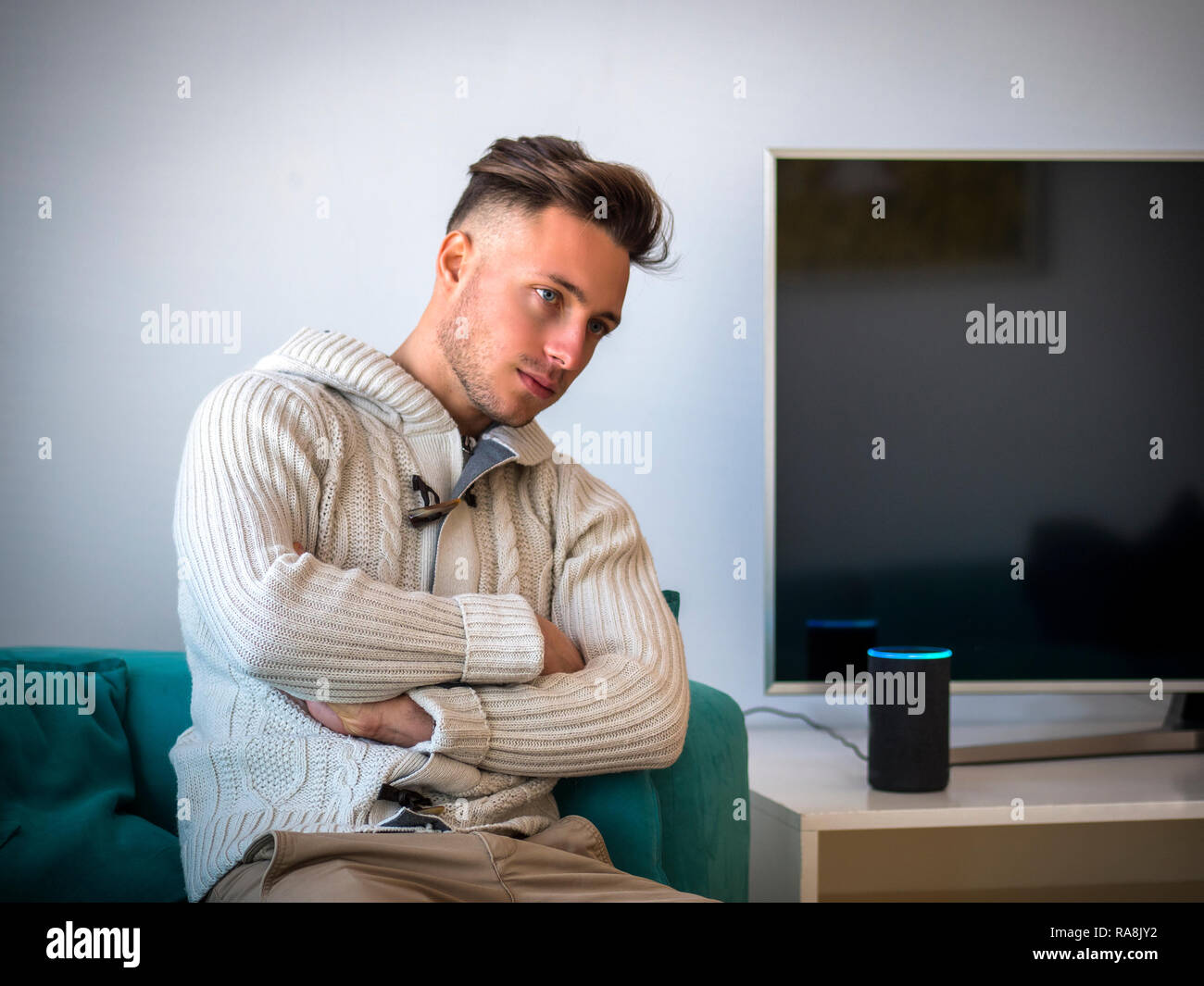 Giovane uomo che parla di smart altoparlante elettronico home assistant Foto Stock