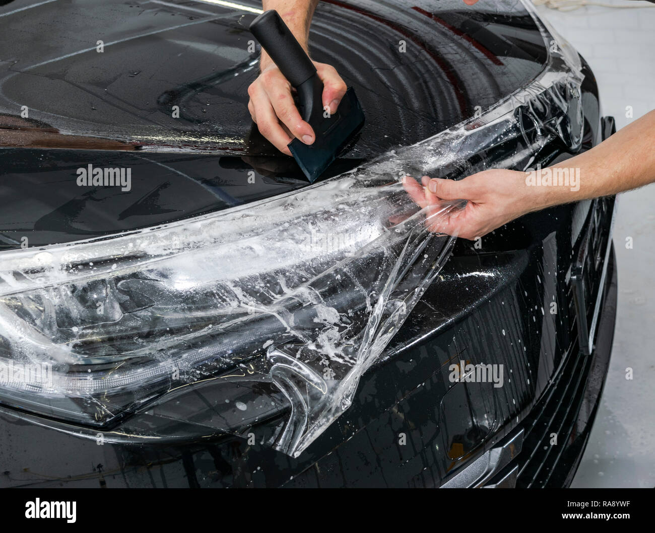 Auto specialista di incarto mettendo vinil lamina o pellicola su auto.  Pellicola protettiva. Applicazione di un film protettivo con attrezzi per  il lavoro. Dettagli auto. Trasparente Foto stock - Alamy