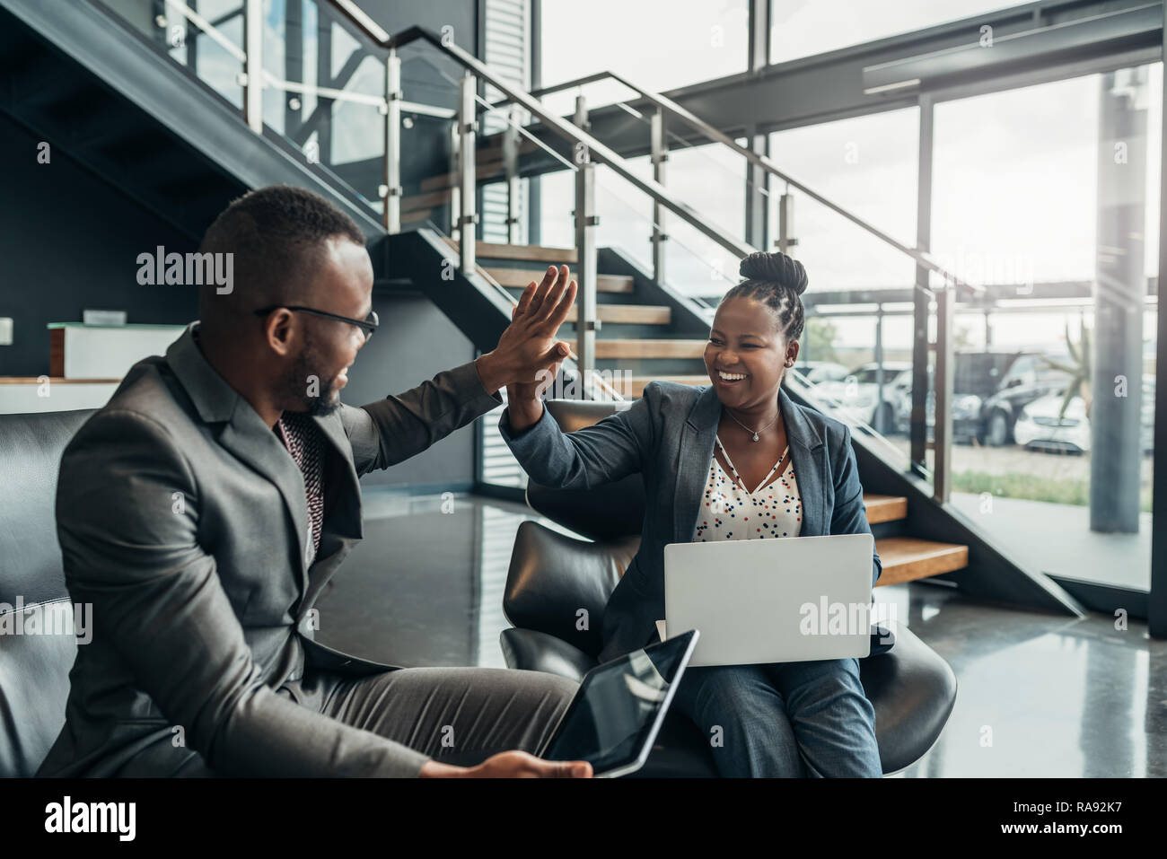 Due amichevoli africano sorridente la gente di affari celerbarting il loro successo con un alto cinque Foto Stock