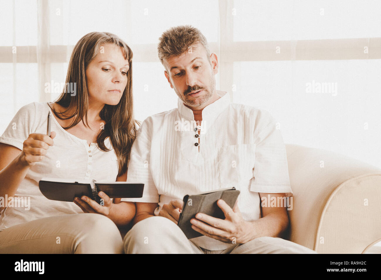 Il marito e la moglie su un lettino nel loro appartamento con una tavoletta e di un blocco note Foto Stock