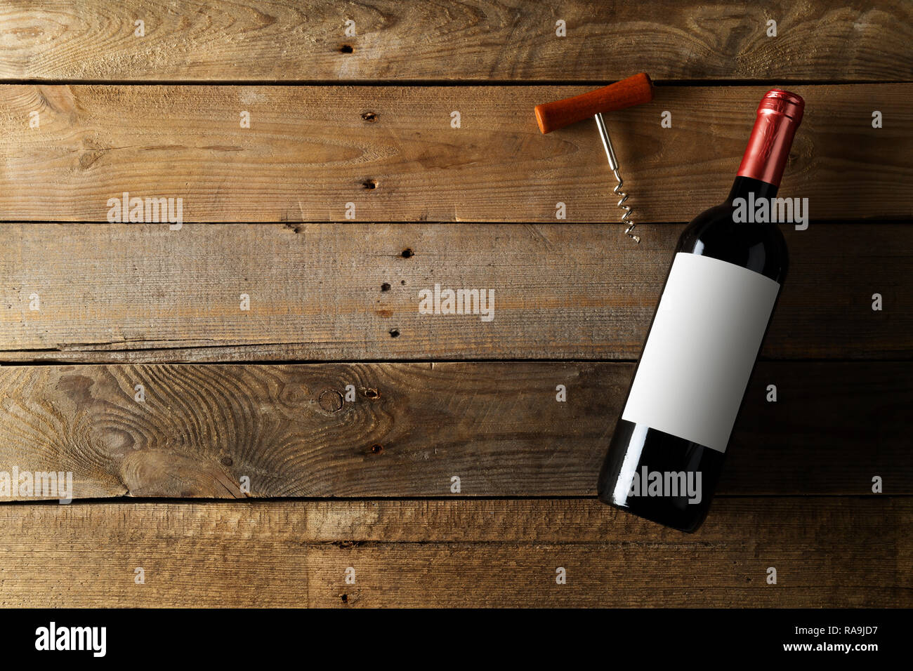 Rosso bottiglia di vino con cavatappi marrone su tavola in legno rustico piana da laici al di sopra con lo spazio di copia Foto Stock