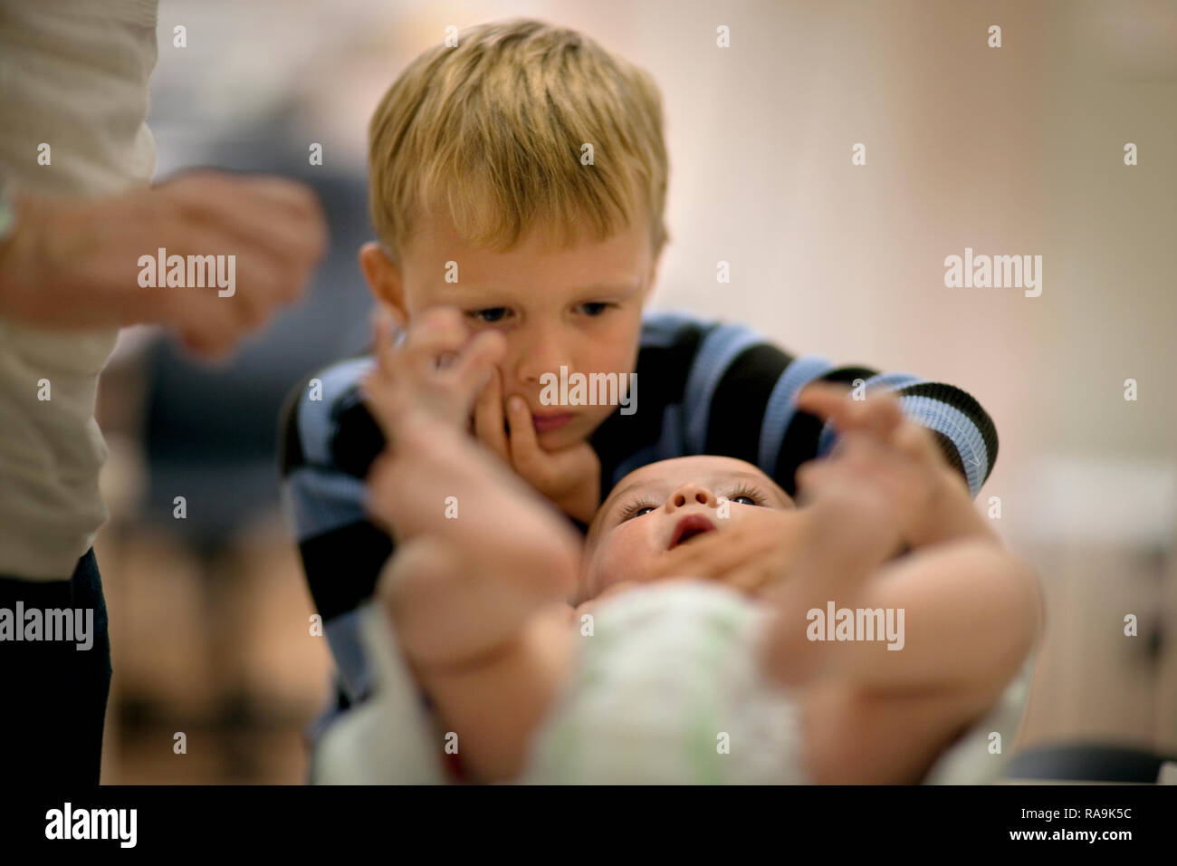 Little Boy curiosamente guardando al suo fratello Bambino giacente sul suo retro. Foto Stock