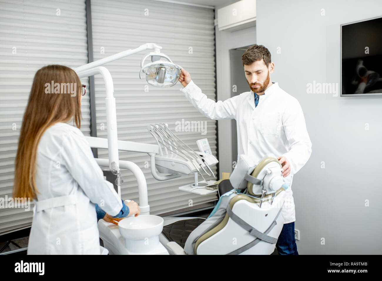 Dentista con assistente donna la preparazione di luogo di lavoro per la procedura in studio dentistico Foto Stock