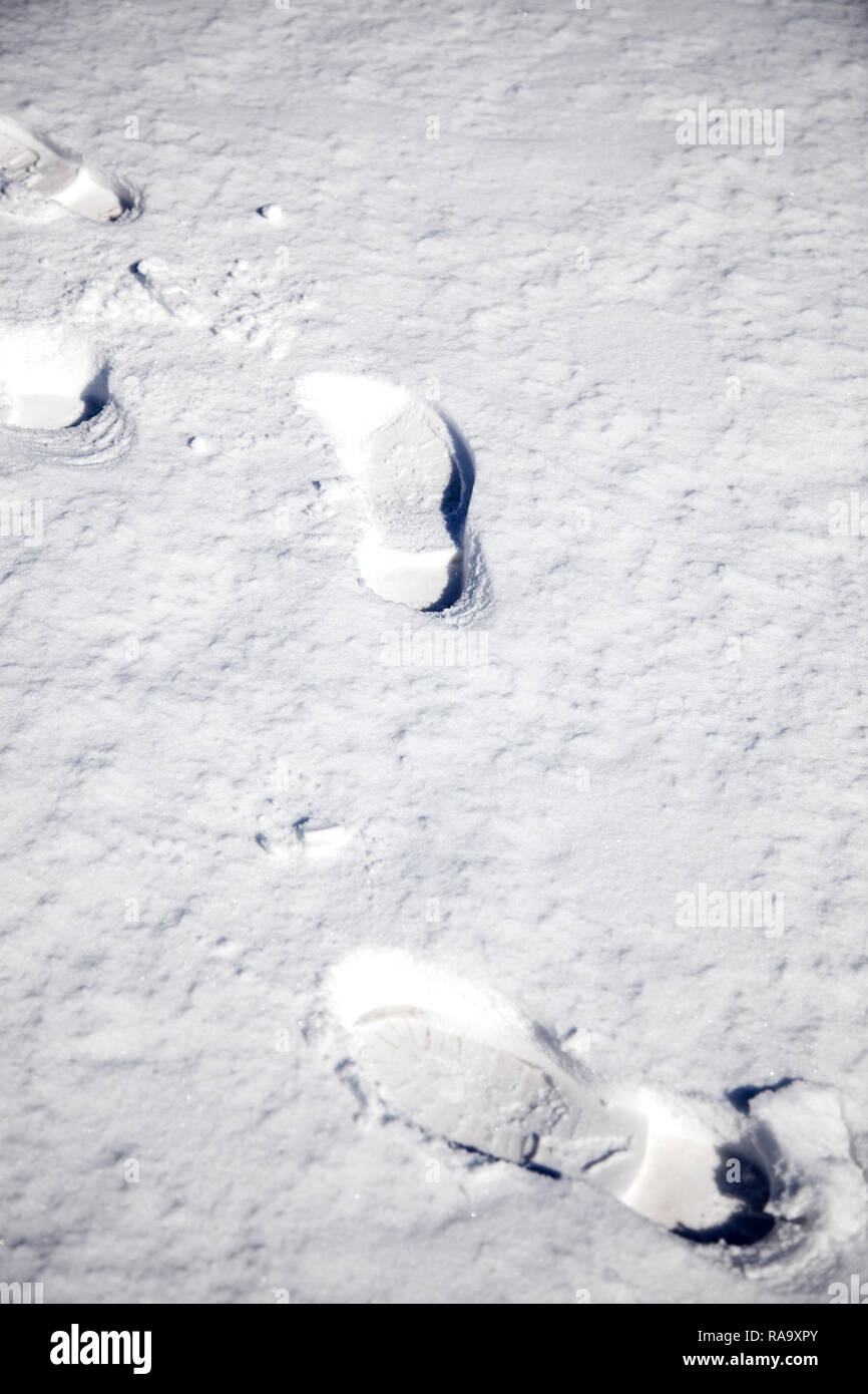 Orme lasciando stampe di avvio su un terreno innevato in inverno Foto Stock