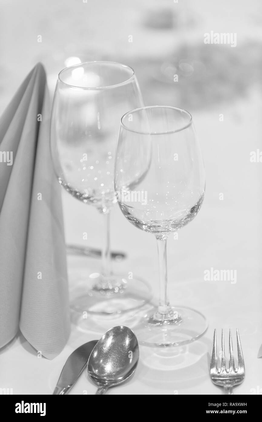 Wineglasses e tavolo ripiegato igienico tishue su ristoranti tavolo ricoperto con tovaglia bianca. Posate e wineglasses servita nel ristorante, vicino. Il servizio del ristorante e concetto. Foto Stock