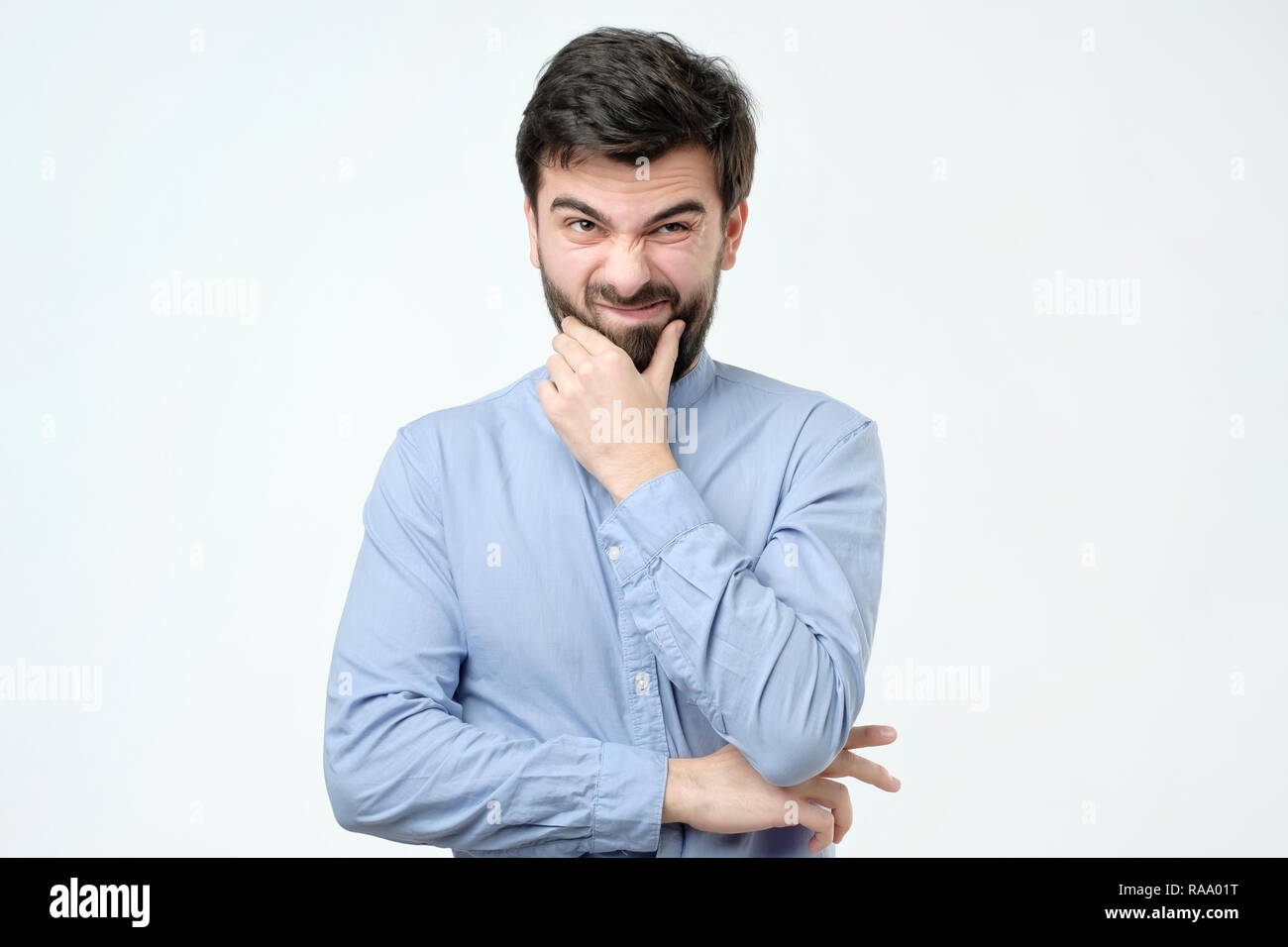 Ritratto di un pensieroso spagnolo Uomo in camicia blu su sfondo bianco. Egli sta cercando di prendere una decisione. Foto Stock