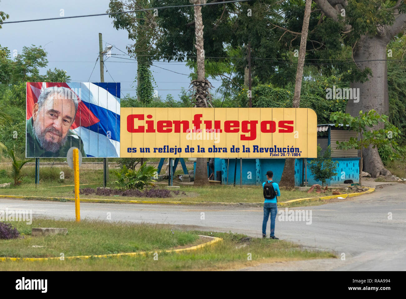 L'uomo attende per bus sotto Fidel Castro propaganda billboard Foto Stock