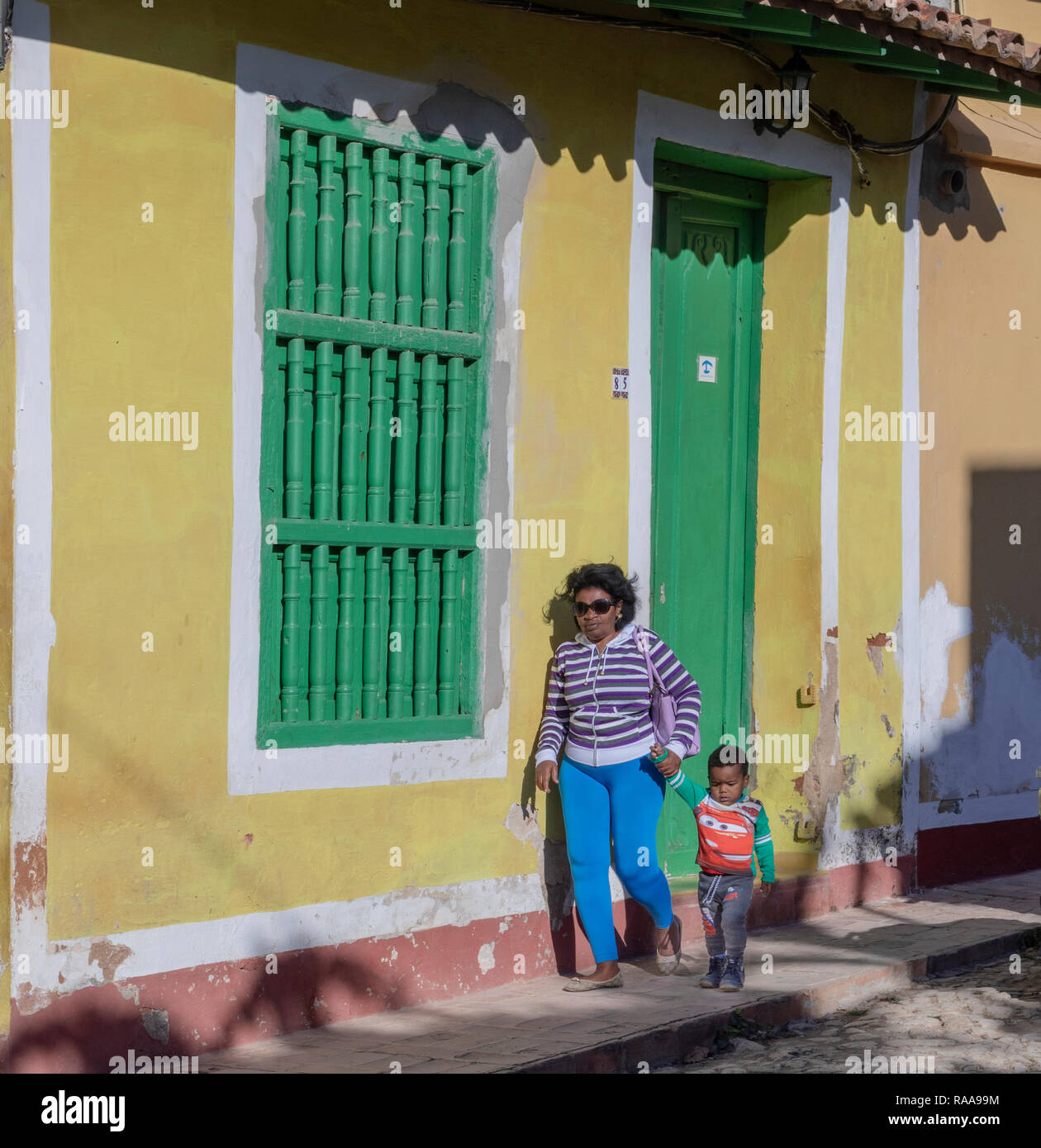 Donna che cammina con ragazzo lungo Calle Real del Jigue, Trinidad, Cuba Foto Stock