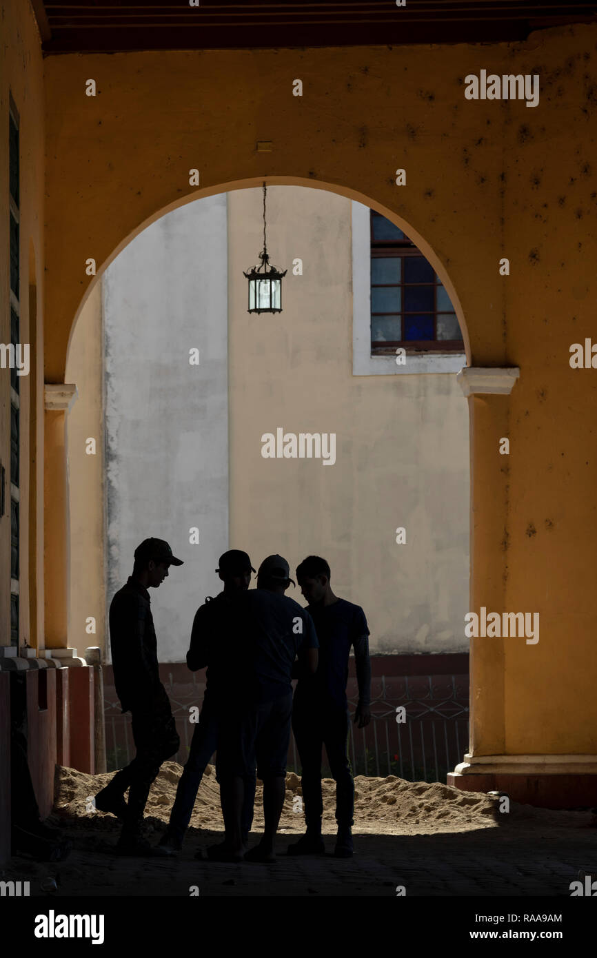 Quattro uomini stagliano sotto arcade di Palacio Brunet, Trinidad, Cuba Foto Stock