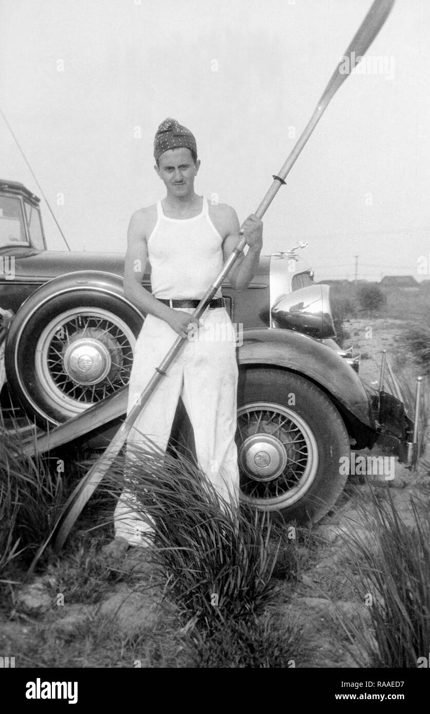 Un giovane uomo sembra pronto a fare un po' di remare lungo la spiaggia in California, ca. 1932. Foto Stock