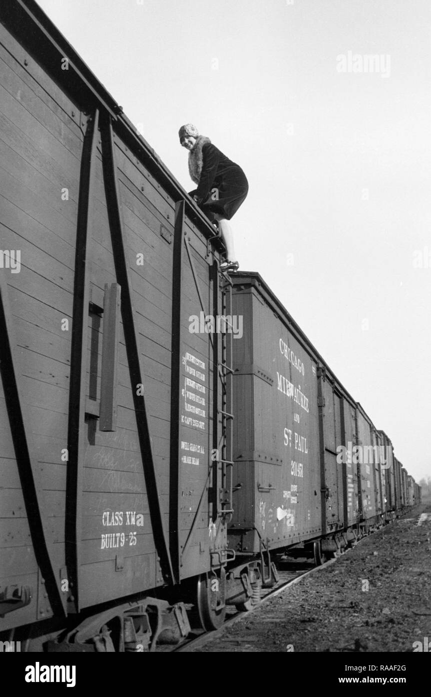 Una giovane donna si arrampica sulla cima di un box auto in Colorado, ca. 1925. Foto Stock