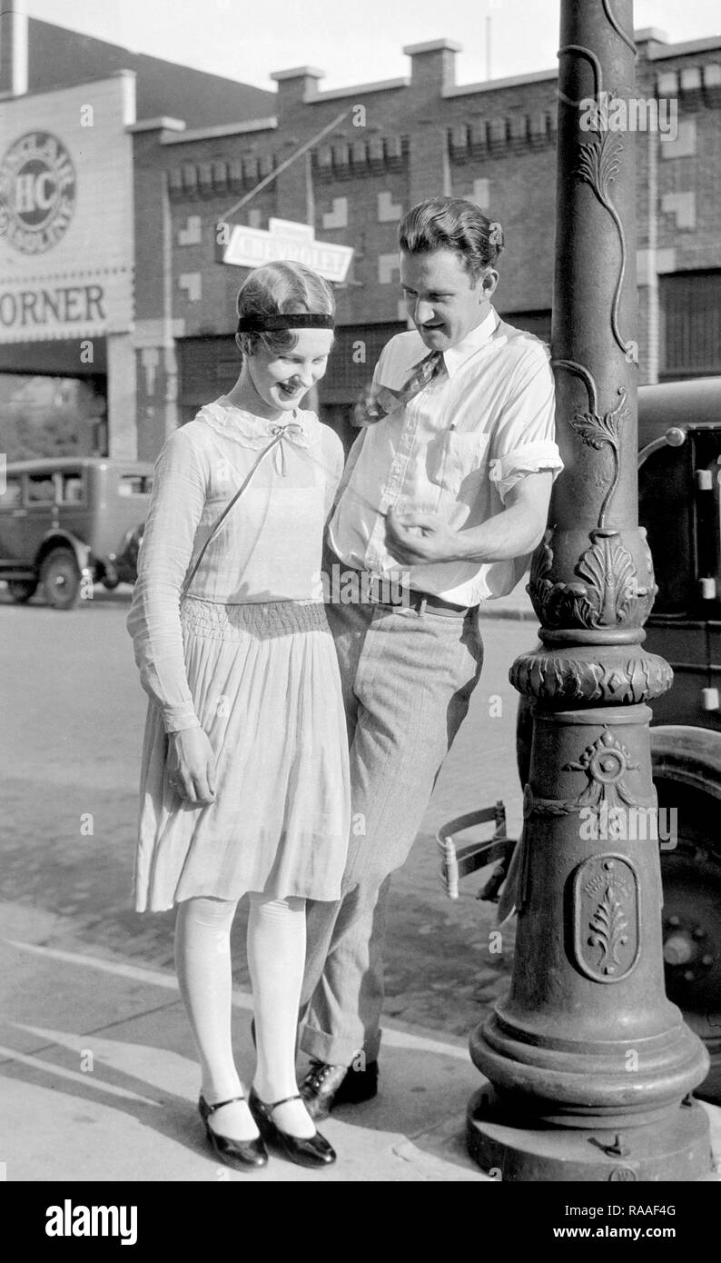 Un uomo flirta con una giovane donna sulla strada, ca. 1925. Foto Stock