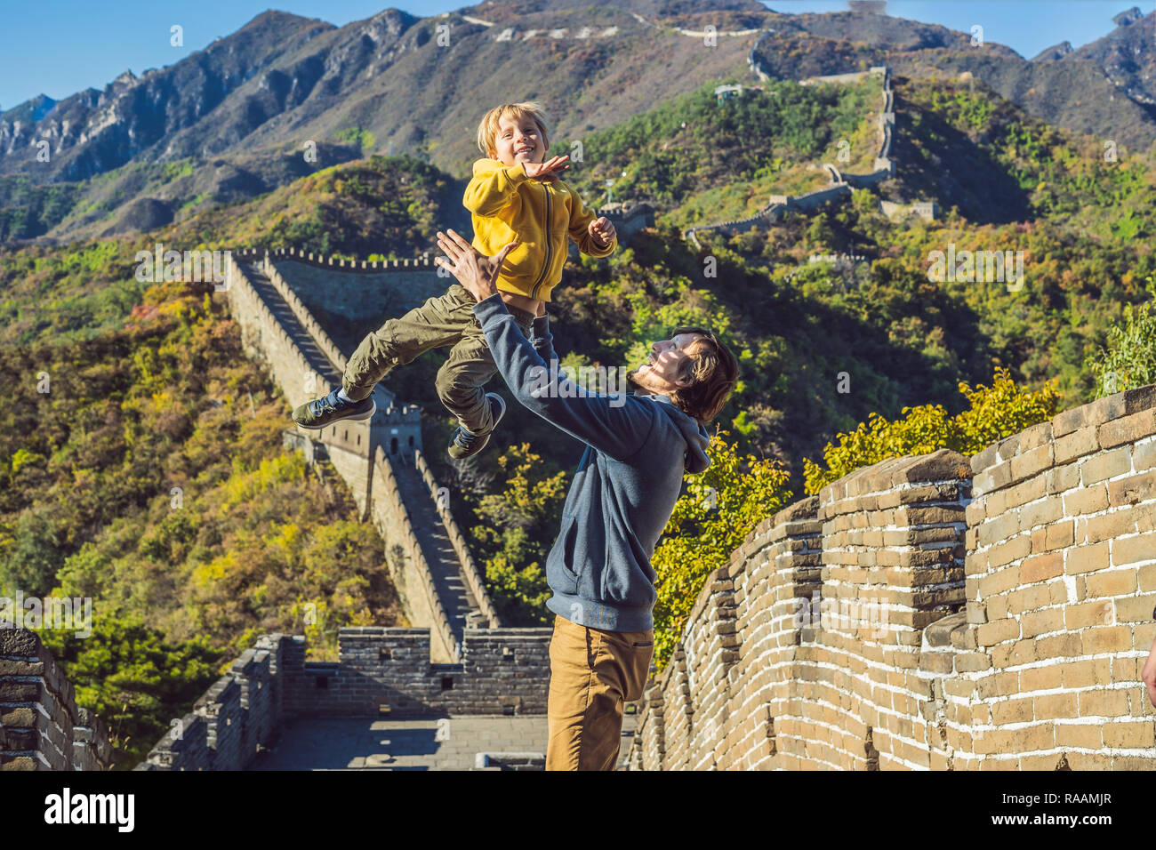 Felice allegro gioioso turisti papà e figlio presso la Grande Muraglia della Cina divertirsi sul viaggio sorridente ridendo e ballando durante il viaggio in Asia. Destinazione cinese. Viaggiare con i bambini in Cina concept Foto Stock