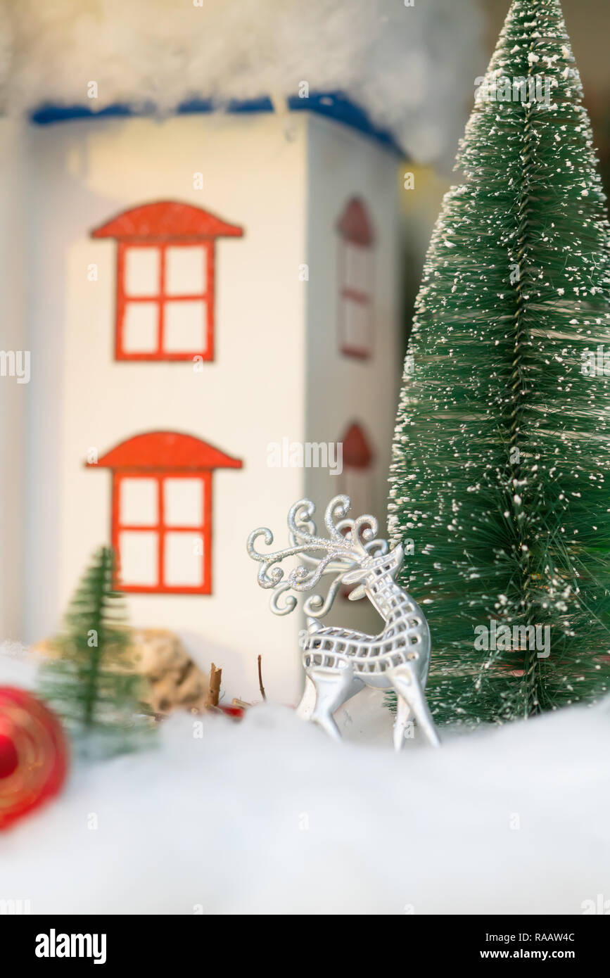 Argento natale renne ornamento con albero nella neve nella parte anteriore di un rustico cottage Foto Stock