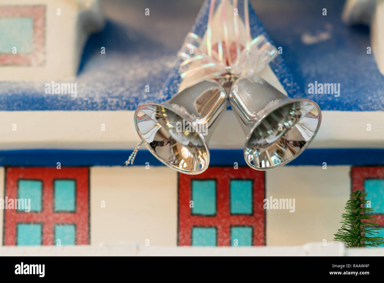Due d'argento Natale campanelle su un nastro nella parte anteriore di un modello di casa con sparsi in inverno la neve Foto Stock