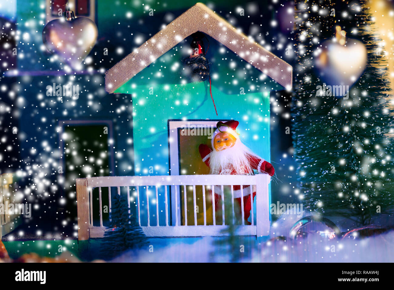Scena di Natale con Babbo Natale sul balcone in piedi a guardare la caduta di neve con cuori di argento in primo piano Foto Stock