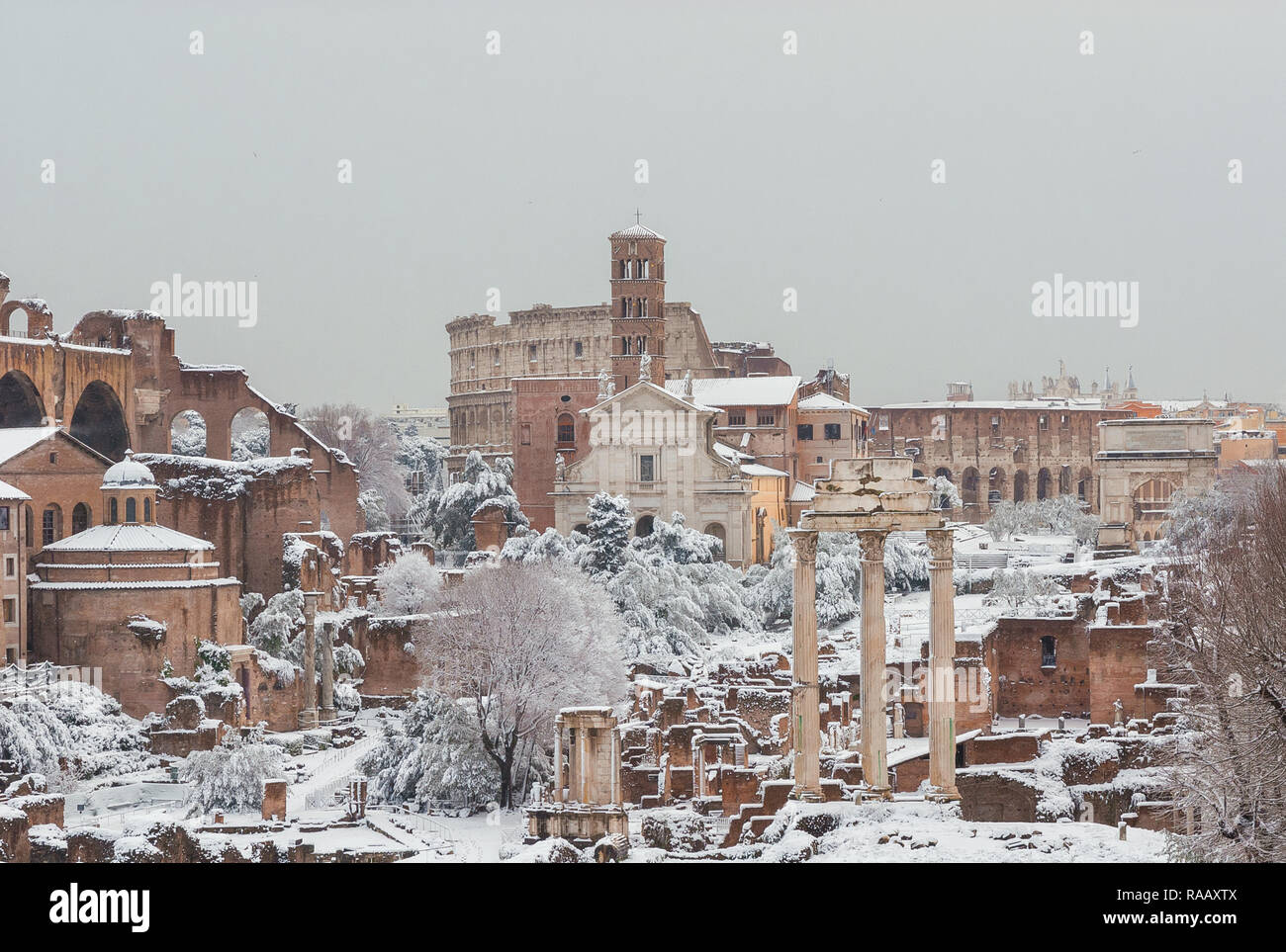 Congelati Roma. Vista del Foro Romano le antiche rovine e il Coliseum coperte da neve Foto Stock