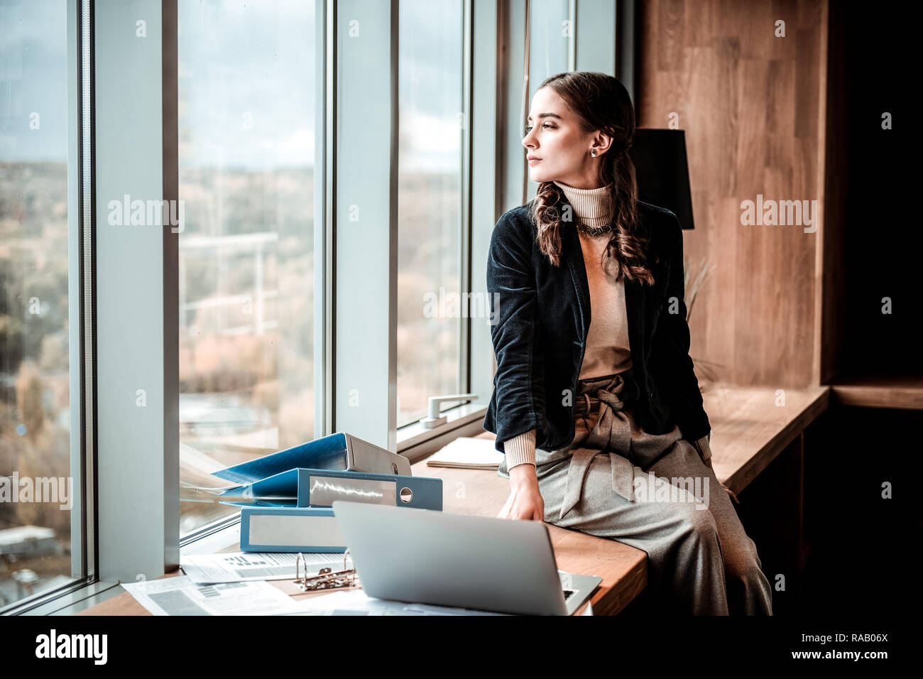 Rilassata longhaired persona di sesso femminile cercando in corrispondenza della finestra Foto Stock