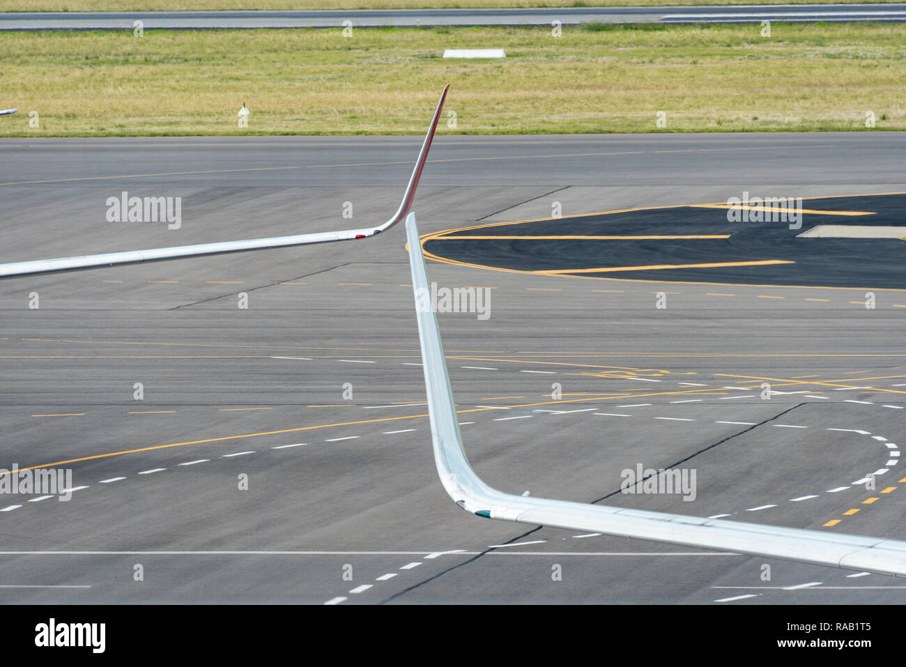 Alette di estremità da due moderni aerei passeggeri contro una pista di sfondo con marcature di linea Foto Stock