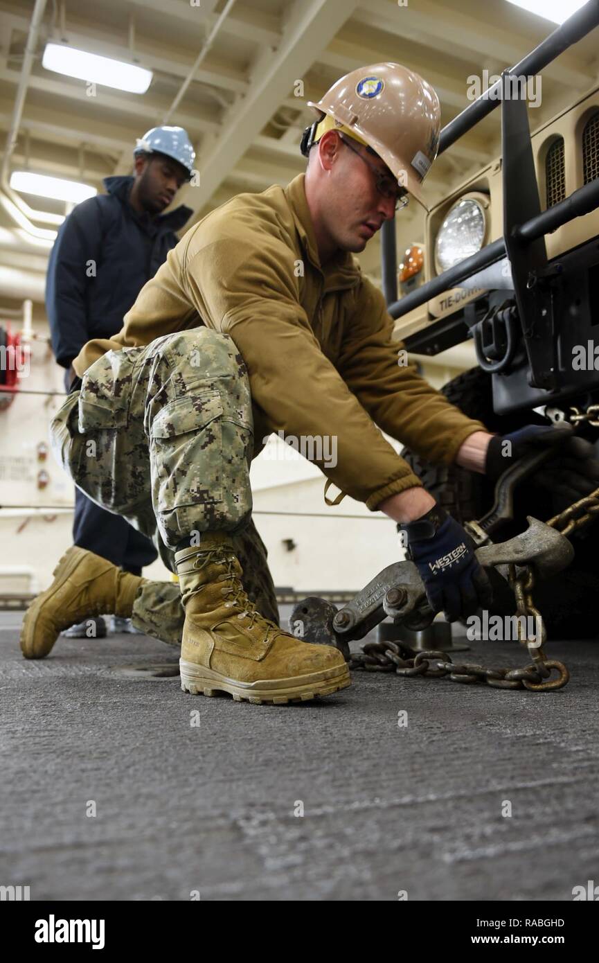 PORT HUENEME, California (Gen. 26, 2017) - Attrezzature operatore Constructionman Marcus Johnson, assegnato alla Naval Mobile Battaglione di costruzione (NMCB) 4, ganci la lamentela e la catena che trattiene l'Humvee in posto sul ponte a bordo di trasporto anfibio dock nave USS San Diego (LPD 22) durante il caricamento di esercizio (LOADEX), 26 genn. Il LOADEX è progettato per la formazione di marinai con risposta rapida funzionalità per supportare gli sforzi di recupero e di assistere le autorità locali seguenti catastrofi naturali e provocate dall'uomo. Foto Stock