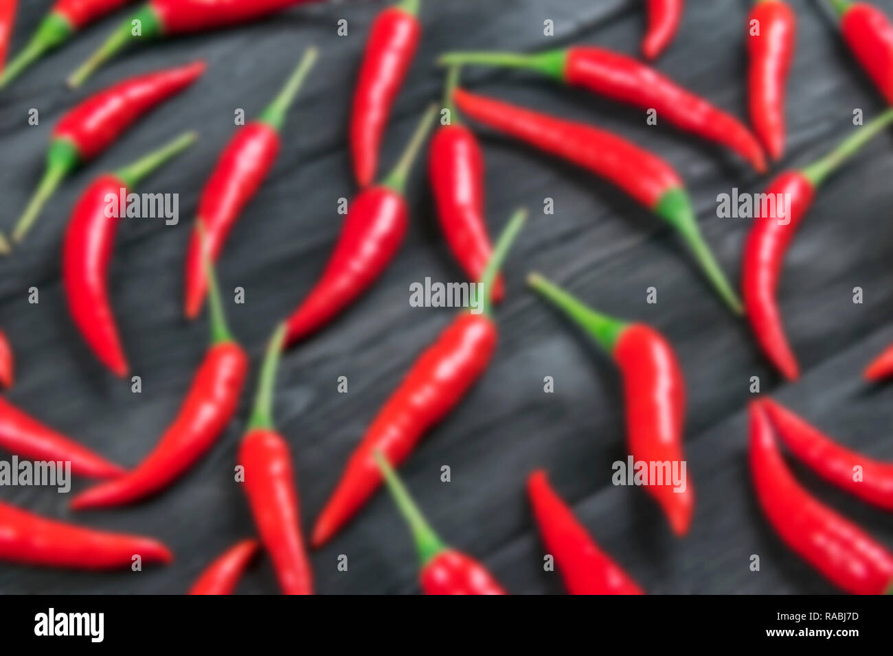 Sfocato sfondo bokeh di fondo con peperoncino rosso sulla sfocatura legno scuro tavolo. Foto Stock