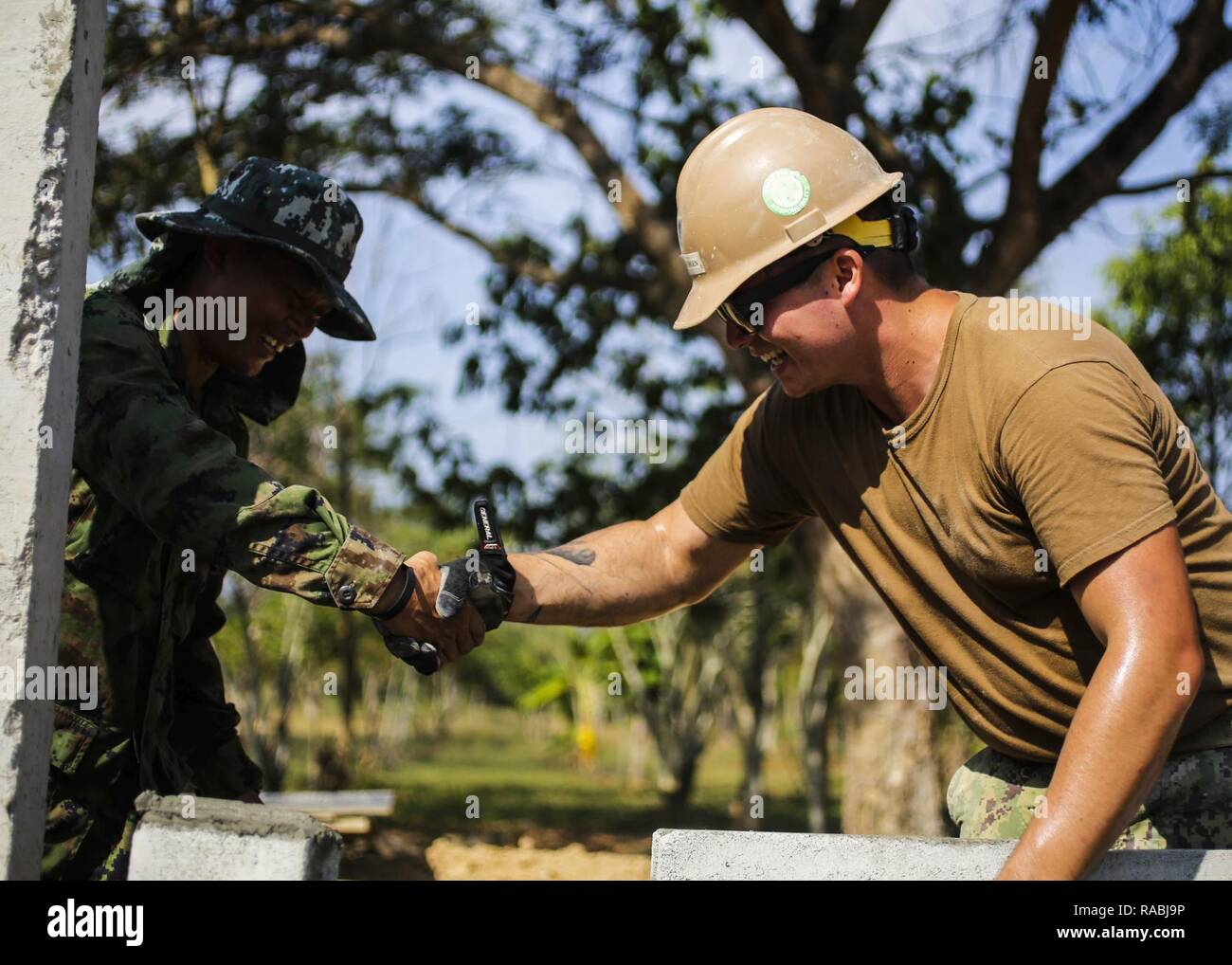 Stati Uniti Navy Petty Officer di terza classe Caspersen Douglas, costruttore navale costruzione Mobile Battaglione cinque, a Peoria, Arizona native, scuote la mano di un Royal Thai Navy Sailor durante la costruzione di una classe al divieto di Nong Mung, scuola di Rayong Thailandia, durante l'esercizio Cobra Oro, Gennaio 30, 2017. Cobra oro, nella sua 36th iterazione, si concentra sugli aiuti umanitari azione civica, impegno nella comunità e le attività mediche per supportare le esigenze e gli interessi umanitari delle popolazioni civili attorno alla regione. Foto Stock