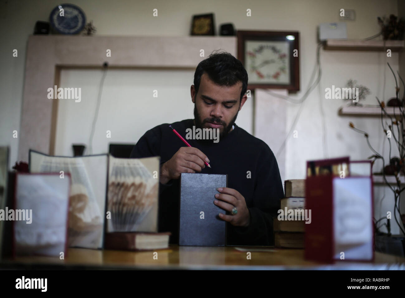 La striscia di Gaza. 31 Dic, 2018. Ahmed Humaid, 28, ripiega a fogli di carta per creare forme e parole dentro la sua casa in Nusseirat Refugee Camp nella zona centrale della striscia di Gaza, a Dic. 31, 2018. Un disoccupati giovani palestinesi l uomo da un campo profughi nella Striscia di Gaza si trova un modo creativo per la lotta contro la disoccupazione tramite l'apprendimento Origami, o la tecnica di piegatura della carta, online. Credito: Stringer/Xinhua/Alamy Live News Foto Stock