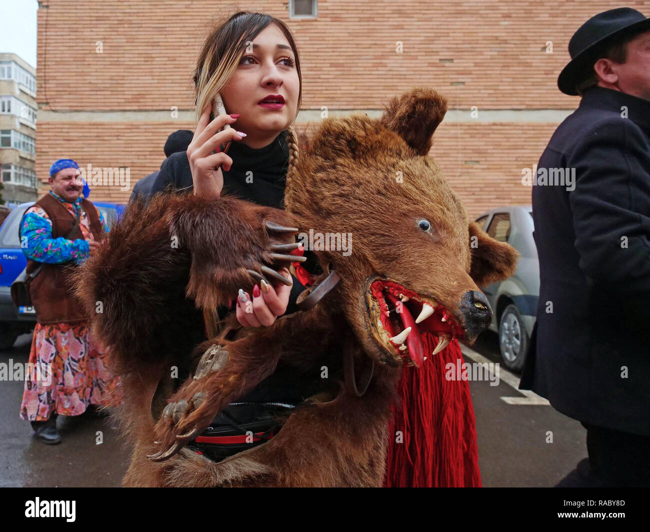 Una donna si vede con un orso pelle durante un fine anno festival. Persone  in Trotus Valley in Romania abito in pelli di orso e danza per scacciare la  sfortuna e portare