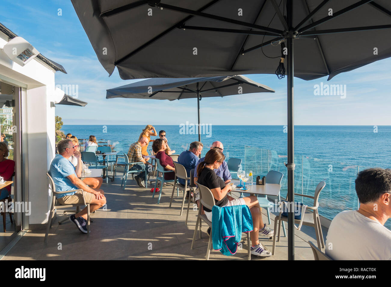 Persone sedute ad alto livello terrazza che si affaccia sul mar mediterraneo, Benalmadena, Andalusia, Spagna. Foto Stock