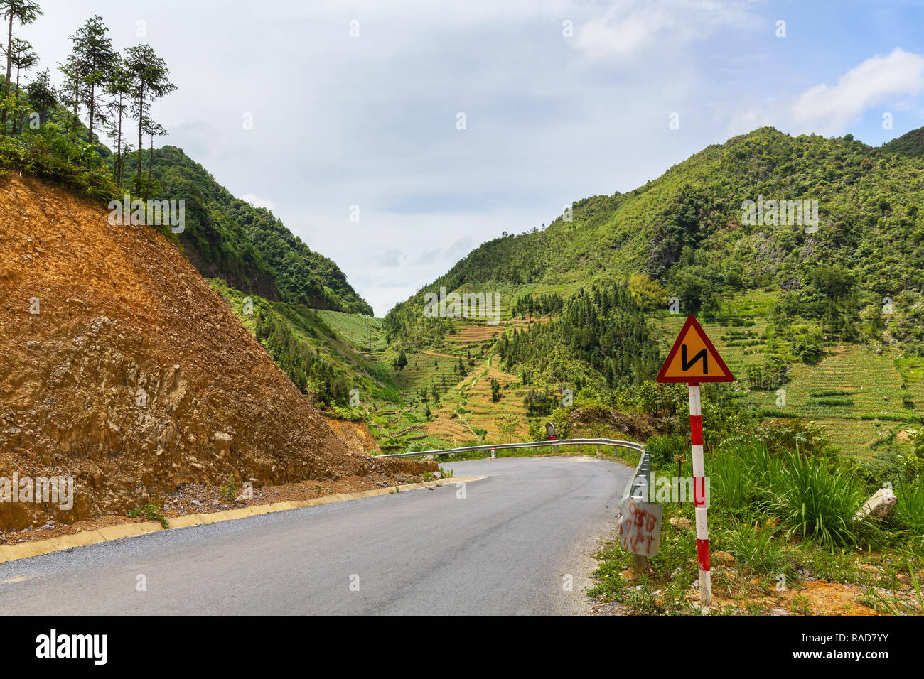 Le curve davanti un cartello di segnalazione su strada sinuosa, Ha Giang Loop, Ha Giang Provincia, Vietnam Asia Foto Stock