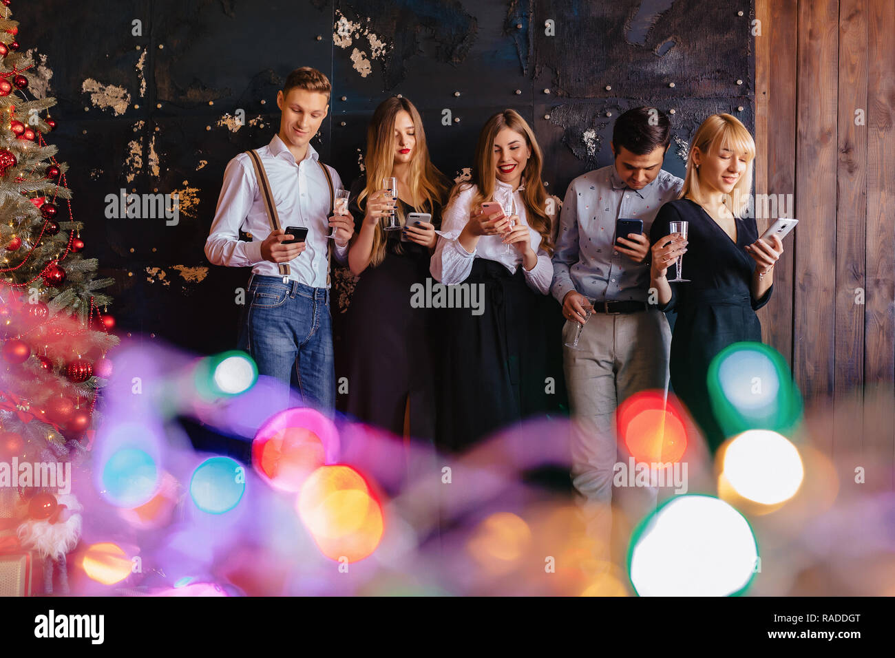 Grande azienda festeggia il nuovo anno con bicchieri di champagne con telefoni mania a casa Foto Stock
