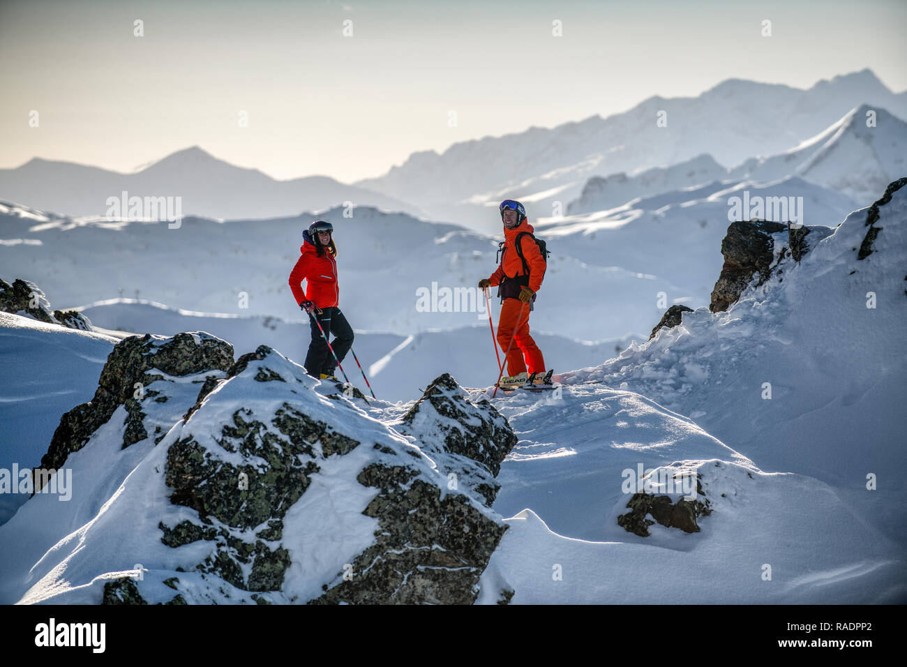 Due gli sciatori stand su una cresta sopra Courchevel guardando fuori attraverso le tre valli ski area nelle Alpi francesi. Foto Stock