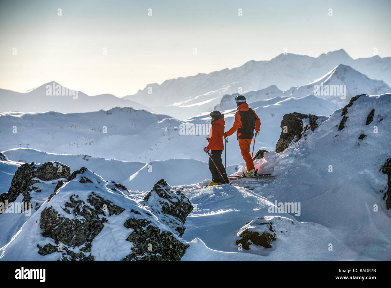 Due gli sciatori stand su una cresta sopra Courchevel guardando fuori attraverso le tre valli ski area nelle Alpi francesi. Foto Stock