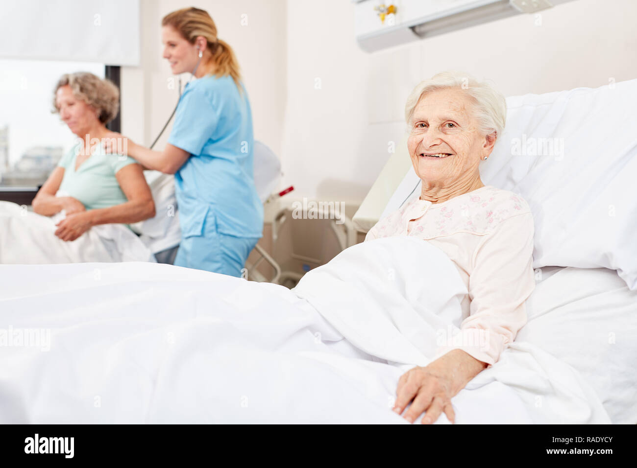 Felice senior donna nel letto di ospedale nella stanza di ospedale in casa di cura Foto Stock