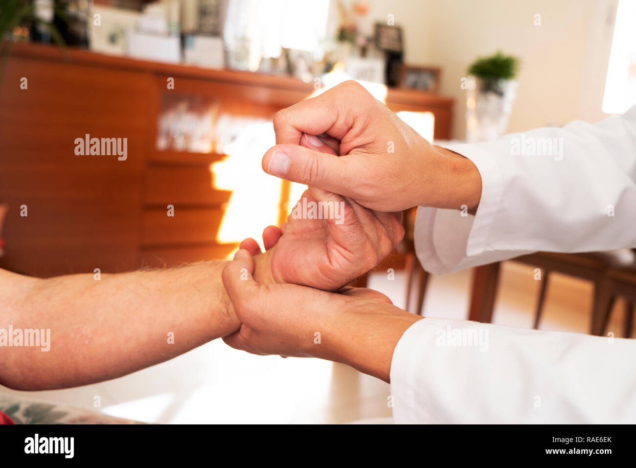 Primo piano di un uomo caucasico, in camice bianco, muovendo la mano di un senior caucasica uomo paziente, a casa sua o in una casa di cura Foto Stock