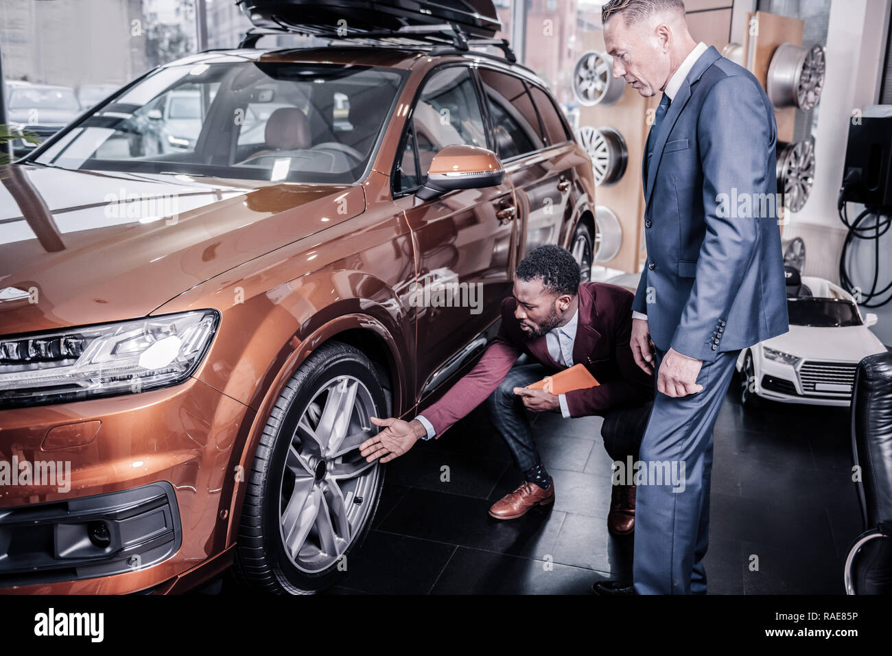 Direttore delle vendite di auto salon raccontando il suo cliente circa le ruote Foto Stock