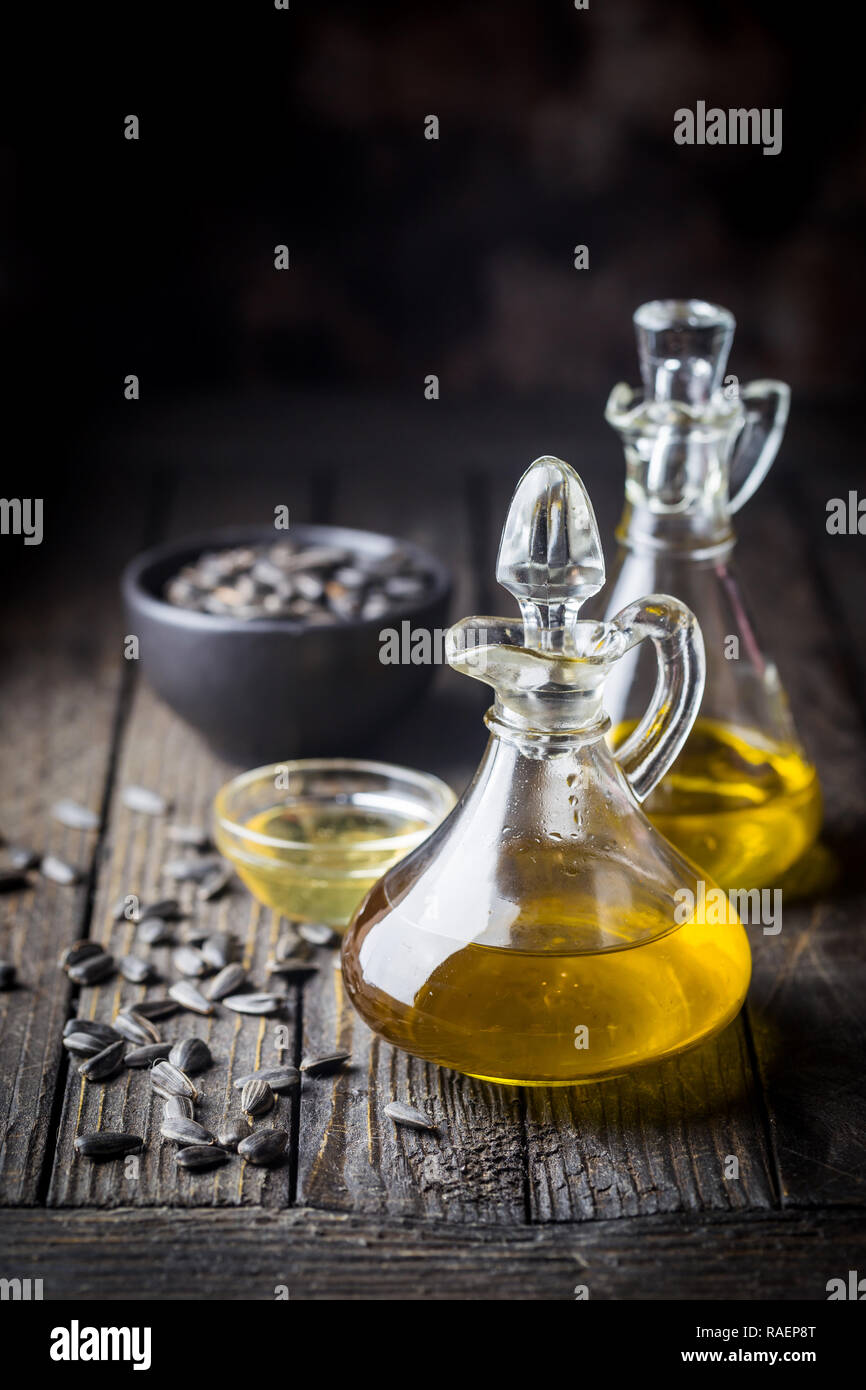 Organici di olio di semi di girasole in un piccolo vaso di vetro con olio di semi di girasole in legno scuro dello sfondo Foto Stock